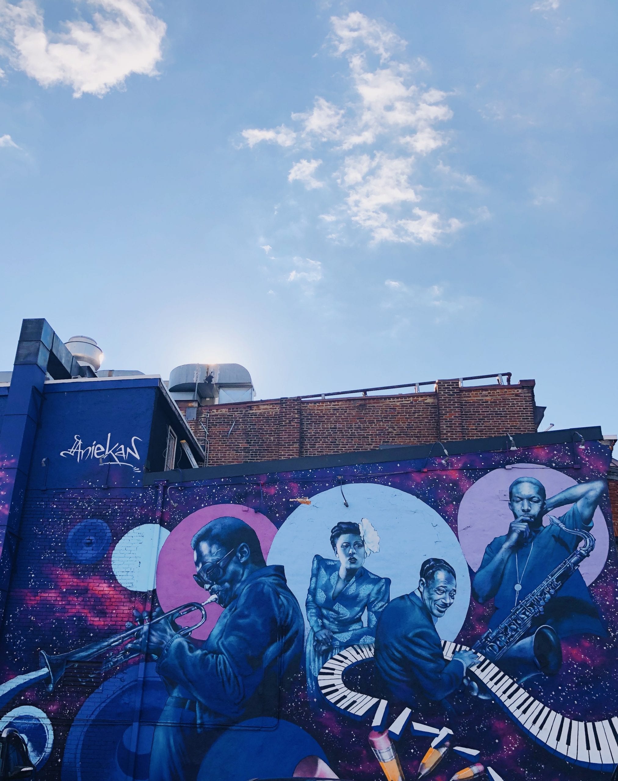 A blue-themed mural on the side of a building with an abstract keyboard and musicians 