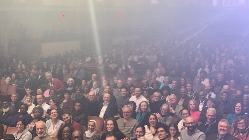 A crowd sitting in one of the Kennedy Center theaters smiling at the camera