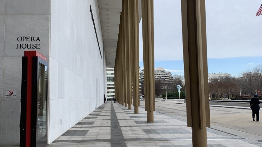 The outside of the Kennedy Center, with the marble building on the left and gold pillars on the right.