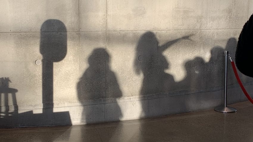 Shadows of a group on a gray wall.