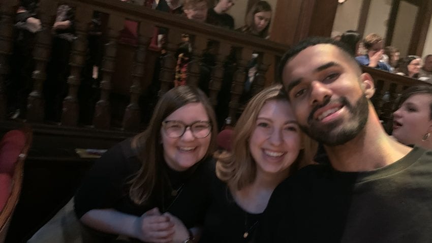 A student takes a selfie with two other students in a theater.