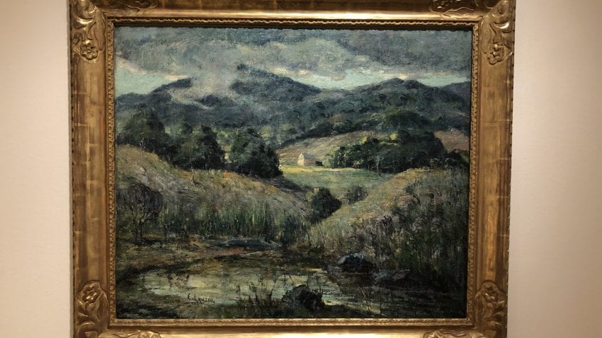 A landscape painting with a pond in the front and hills covered with trees
