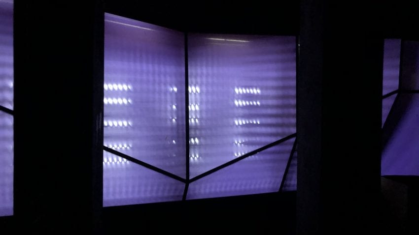 A purple wall with a backlight and two black pillars on each side. 