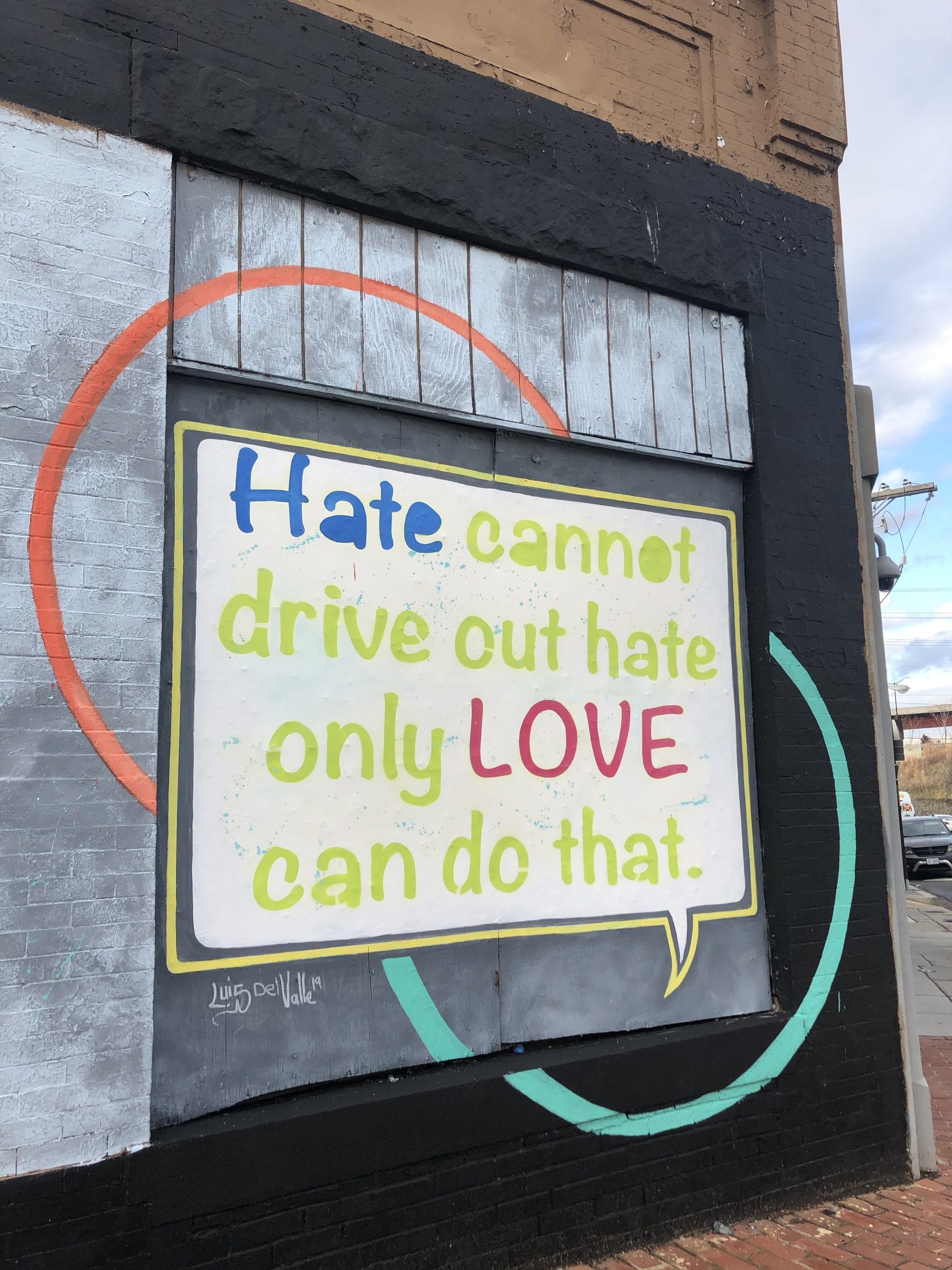 A colorful sign reading "Hate cannot drive out hate. Only Love can do that" with a metal background