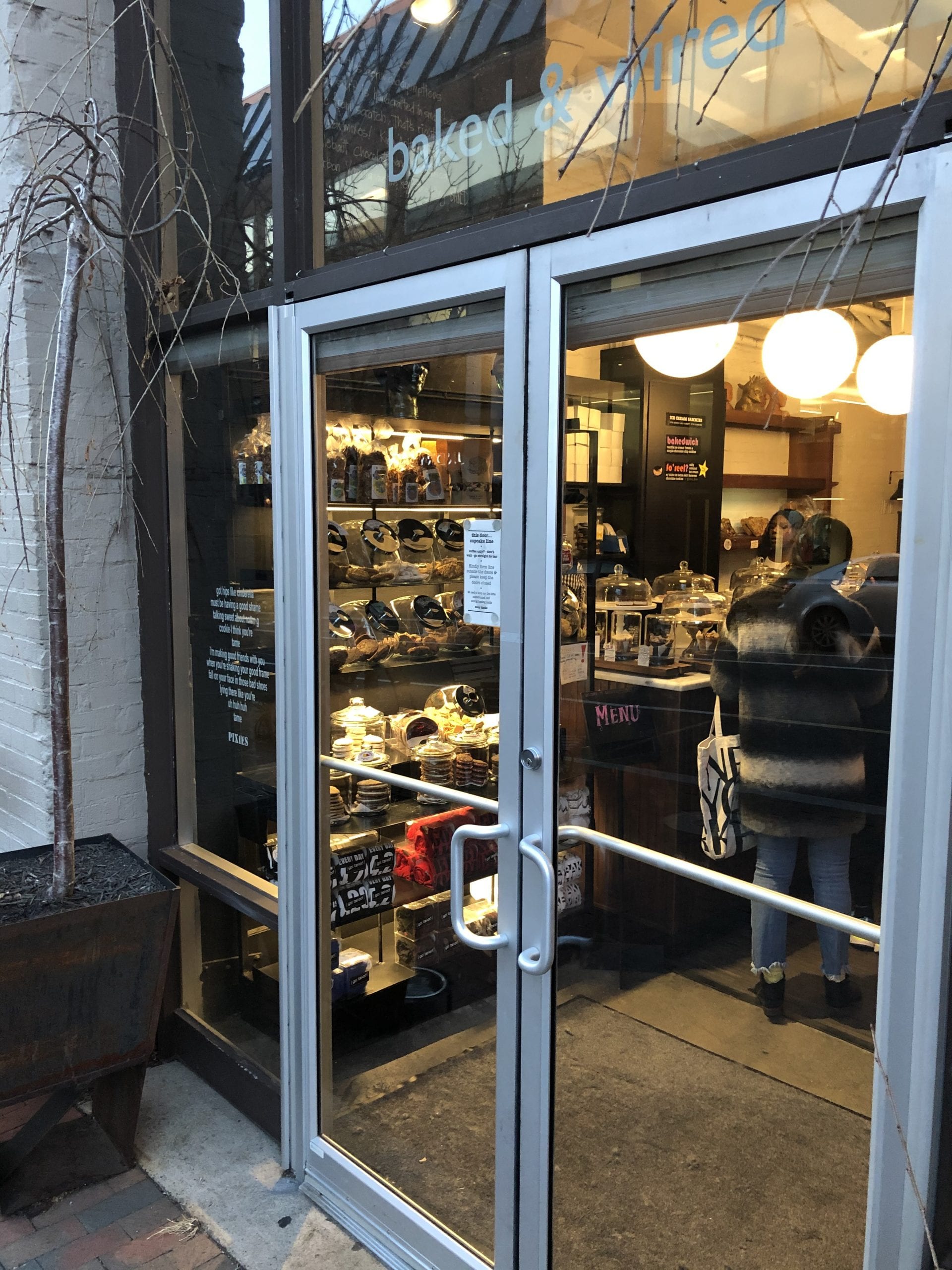 A pair of glass doors where you can see a long line next to a wide array of baked goods