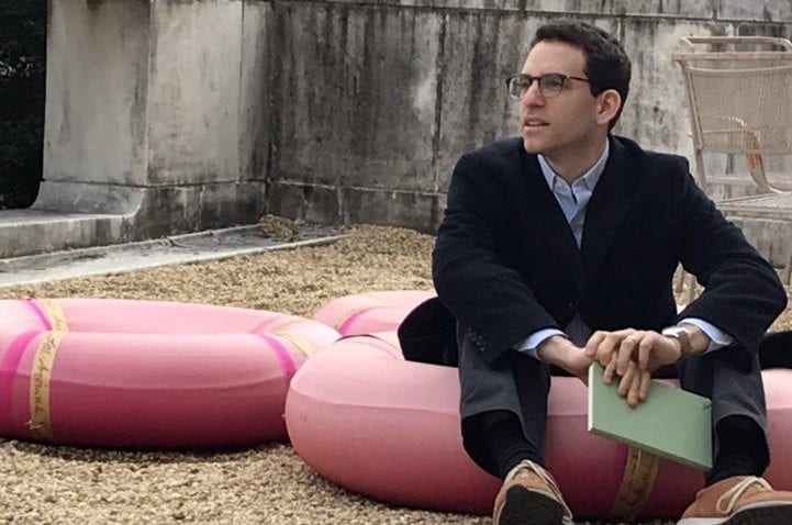The St. Olaf professor sits in a red inner tube next to an empty red inner tube on a rocky ground