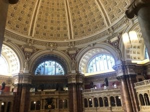 The Library of Congress reading room with a large domed ceiling and various levels of bookshelves.