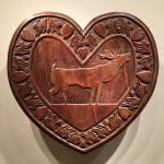 A wooden heart with a carving of a moose.