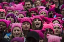 A crowd wearing pink hats and chanting. 