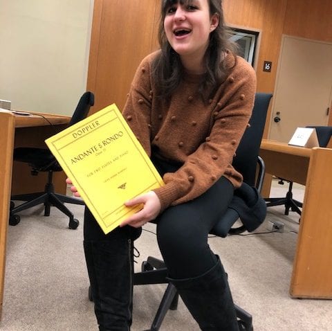 A student sits with a yellow music score
