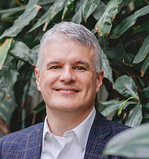 Images shows a headshot of Paul with plants in a greenhouse in the background.