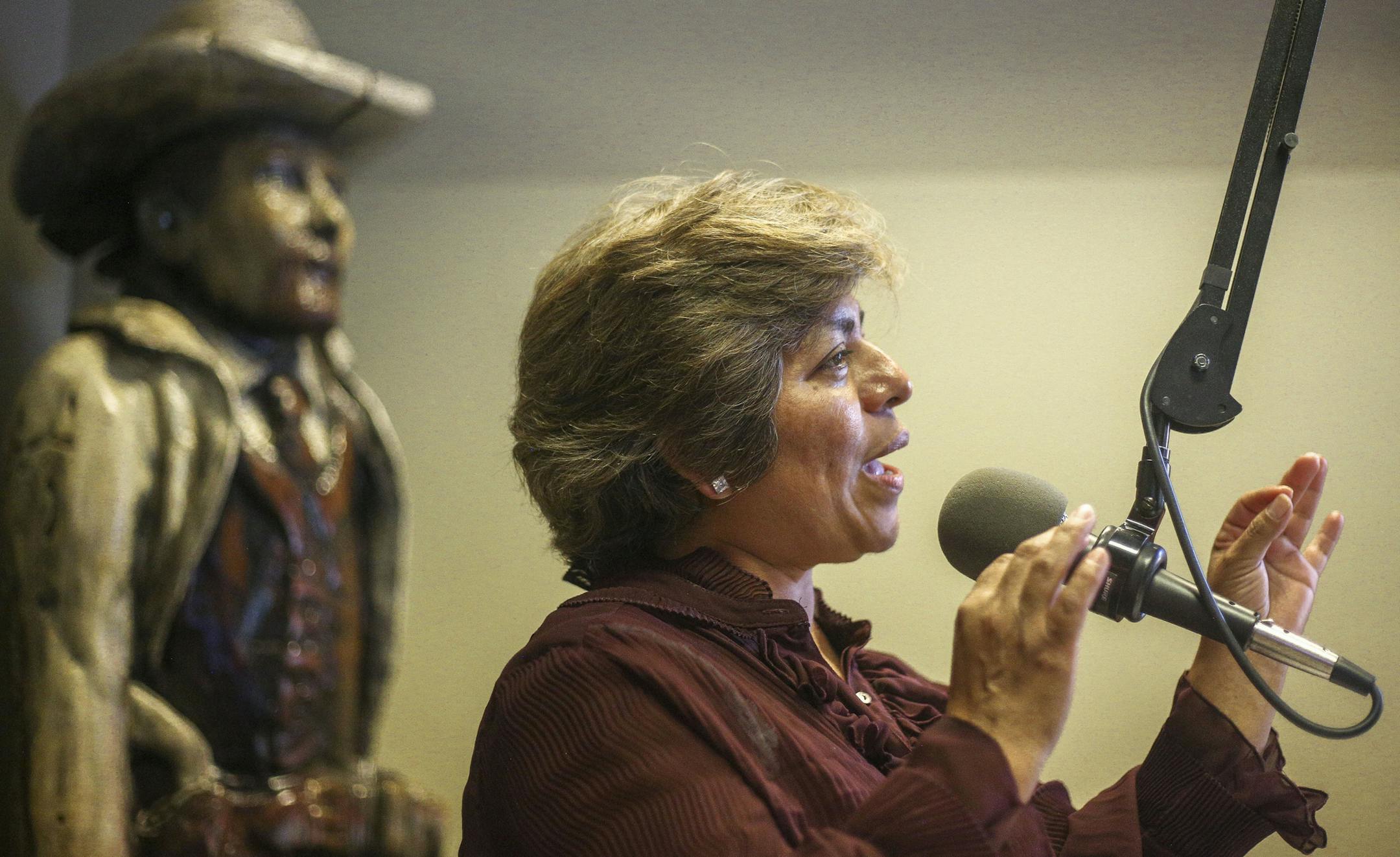 An old woman with a red shirt holding a microphone.