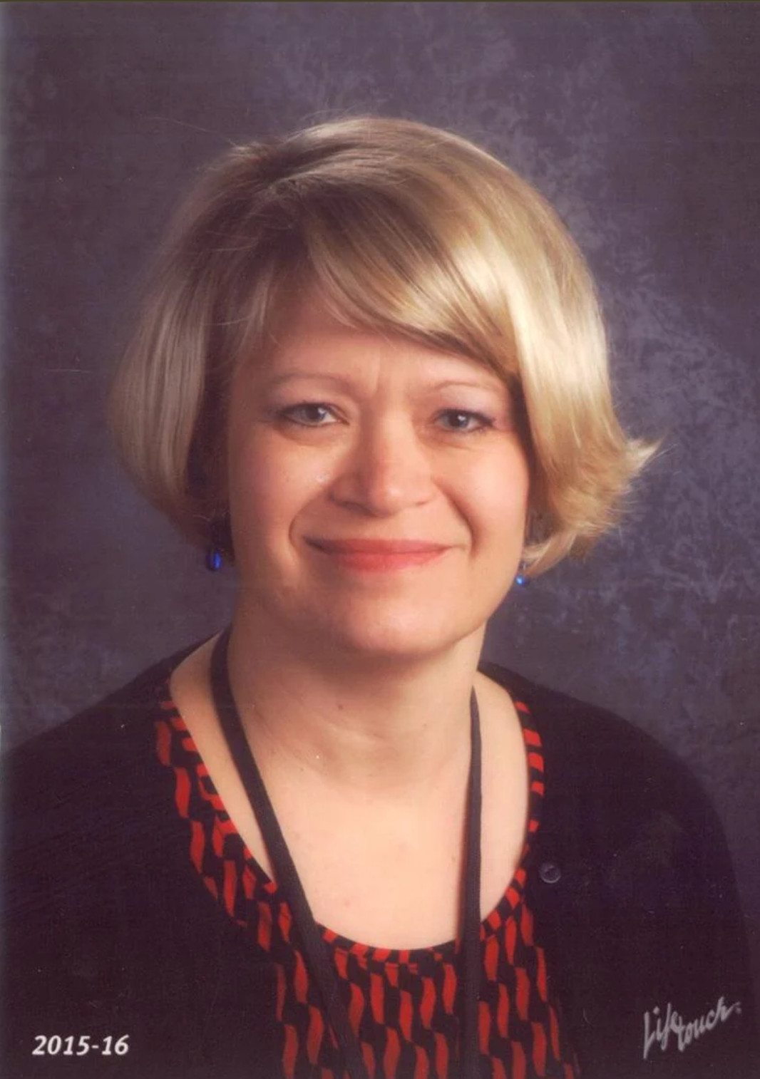 White blonde woman with red and black dress smiling at camera