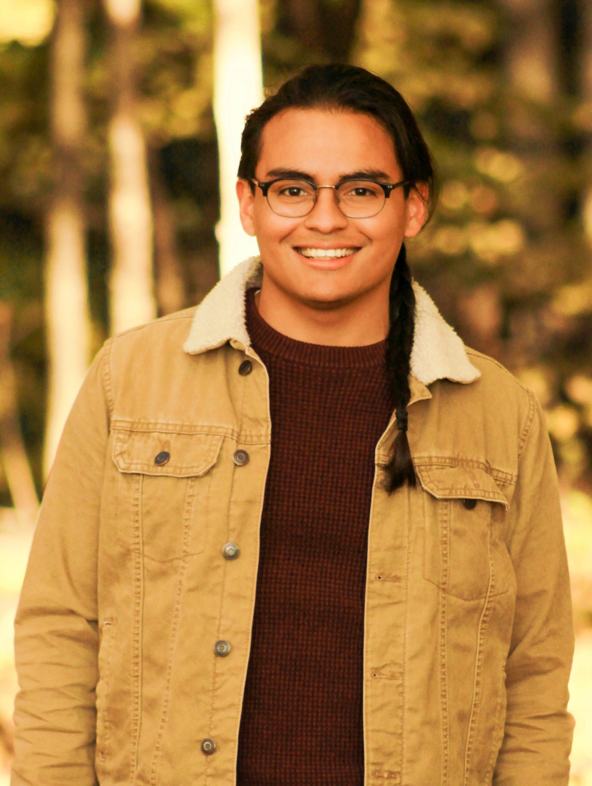 Latino guy with a braid standing.