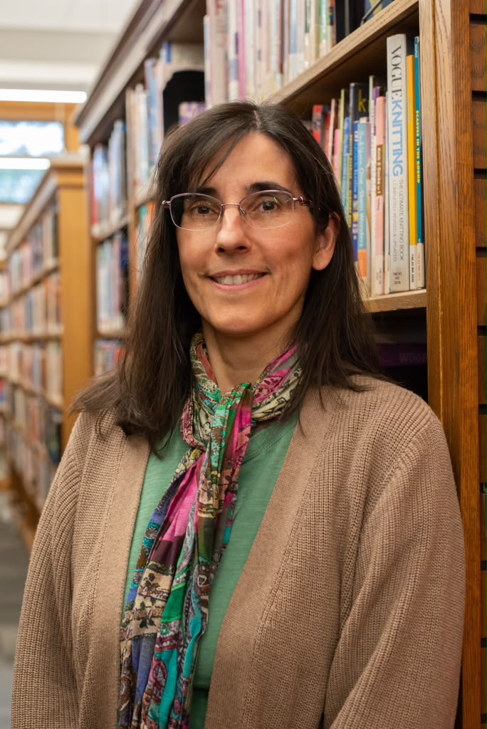 Woman smiling to camera with glasses and red shirt.