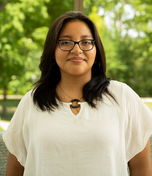 Young Latina girl with glasses and white blouse.