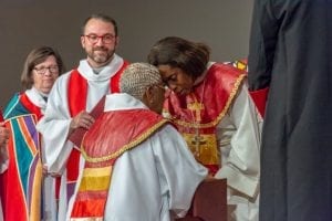 Bishops Thomas-Breitfeld and Davenport, both wearing formal bishop's robes, kneel facing each other with their foreheads touching. Their eyes are closed while they pray upon the occasion of Bishop Davenport's installation.