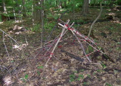 Tipi structure made of branches in the woods.