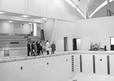 A group of people examine the unfilled new swimming pool.