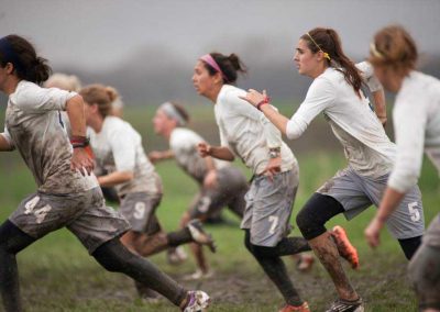 Women's Ultimate Frisbee Team running through mud for game.