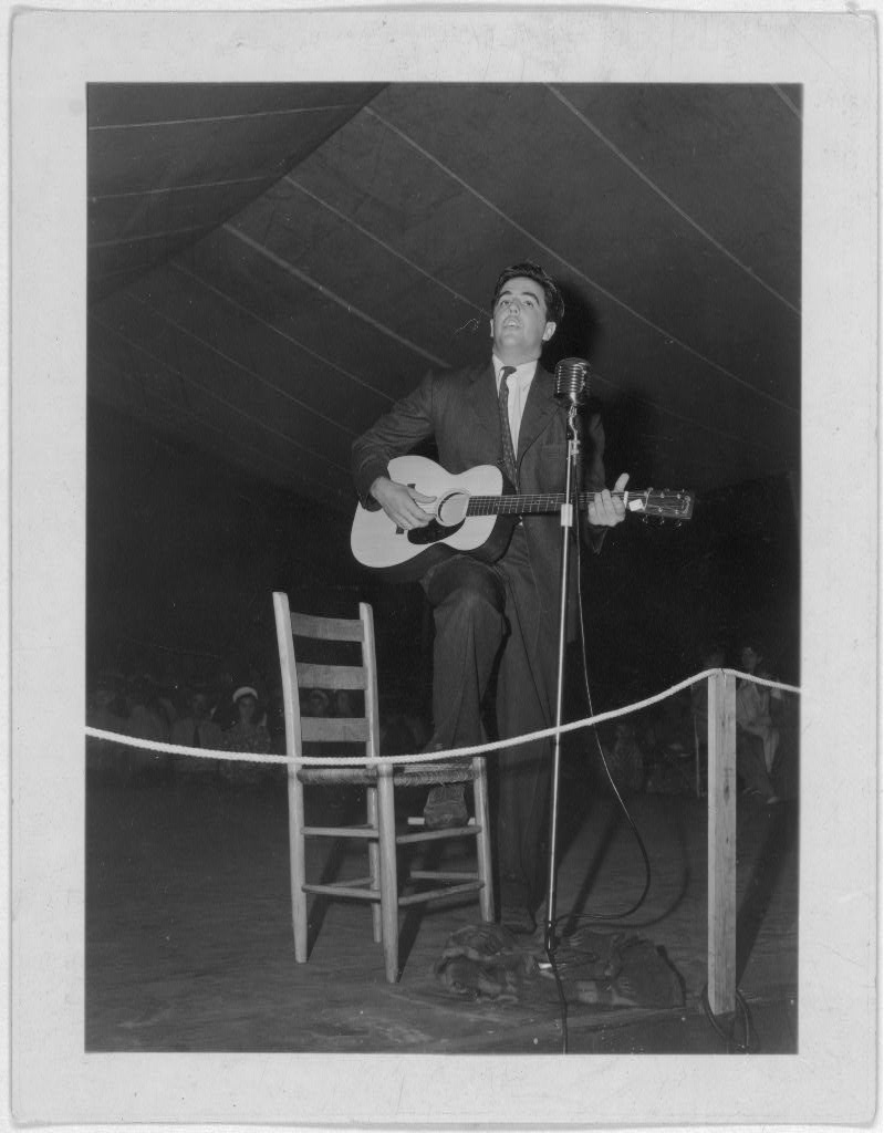 Alan Lomax playing guitar on stage at the Mountain Music Festival, Asheville, N.C.
